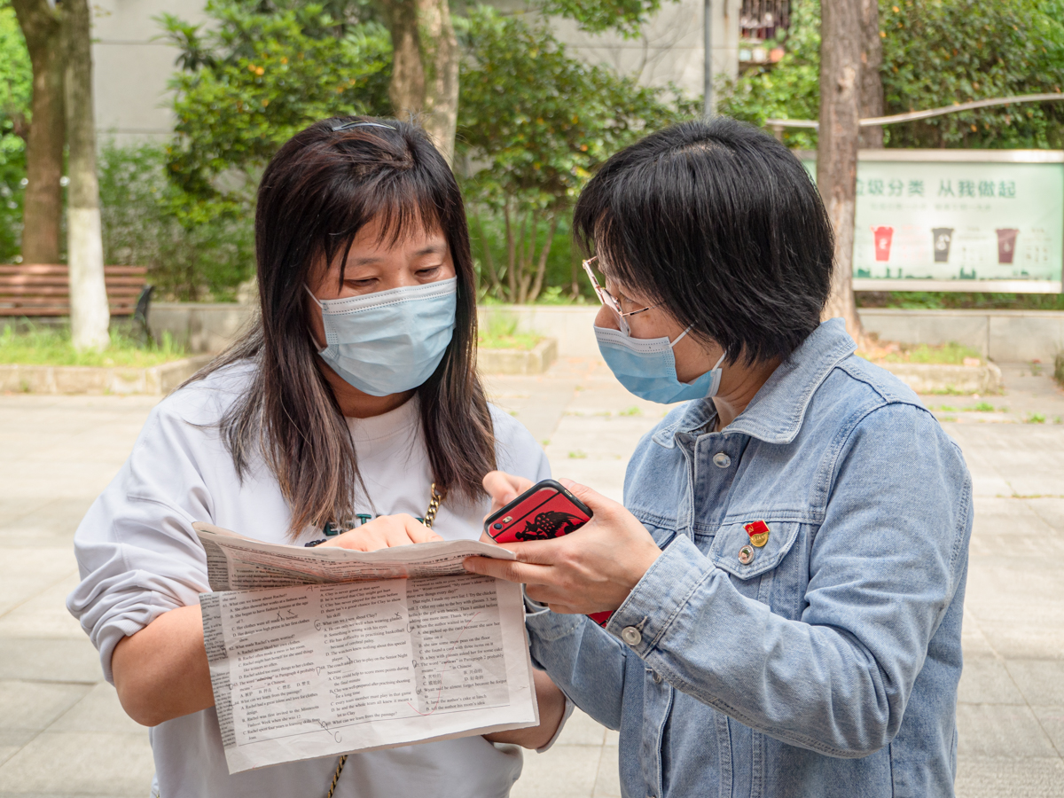 老师与家长就学生英语报作答情况讨论孩子学习方法（学通社记者 邓颖骏 摄）